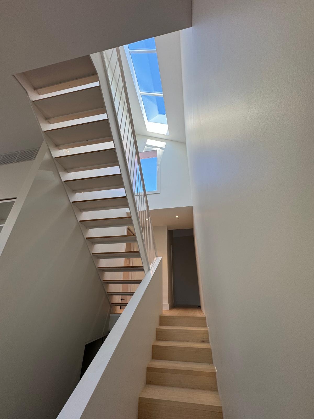 Open-tread staircase with timber treads rising toward a skylight